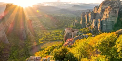 A scenic view of the sun rising over Meteora Monasteries in Greece