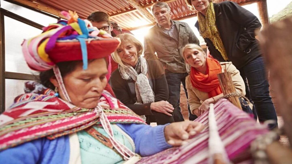 Trafalgar guests watching a Peruvian woman doing traditional weaving