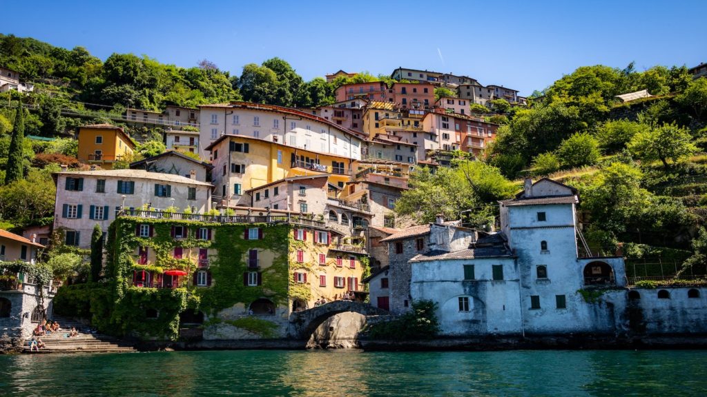 One of the waterfront 'cinque terra' villages, houses climbing a lush green hillside overlooking turquoise sea, seen from sea level