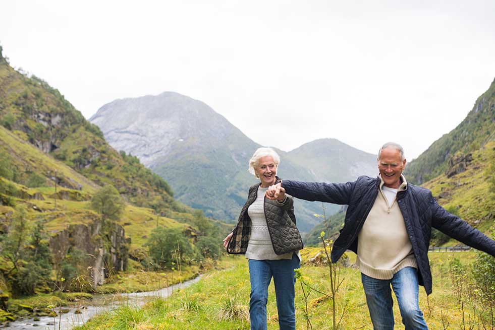 elderly couple walking through hills