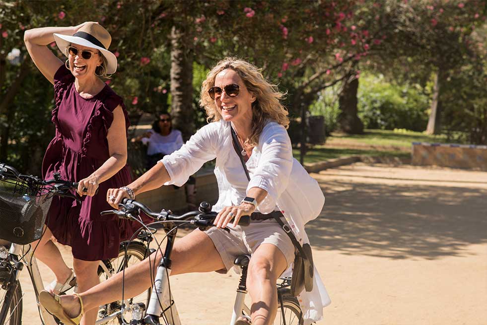 two women laughing and riding bikes
