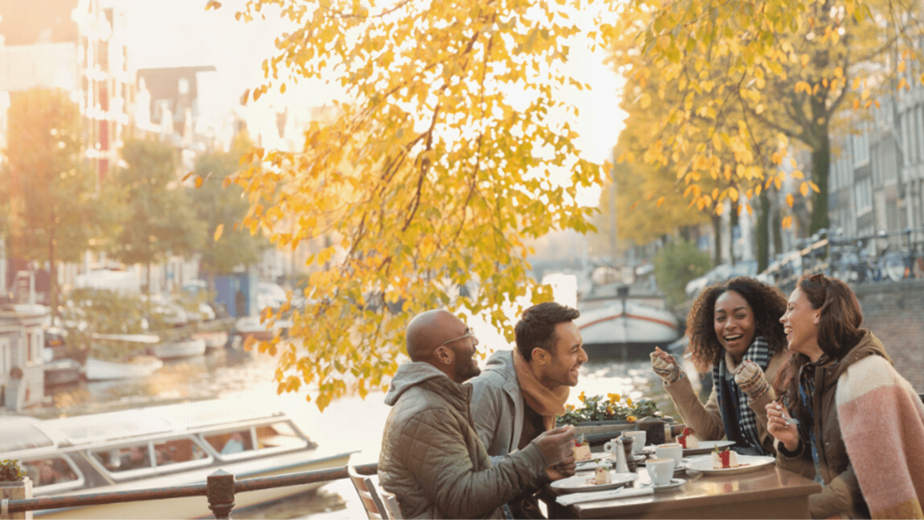 four people laughing and having lunch outdoors