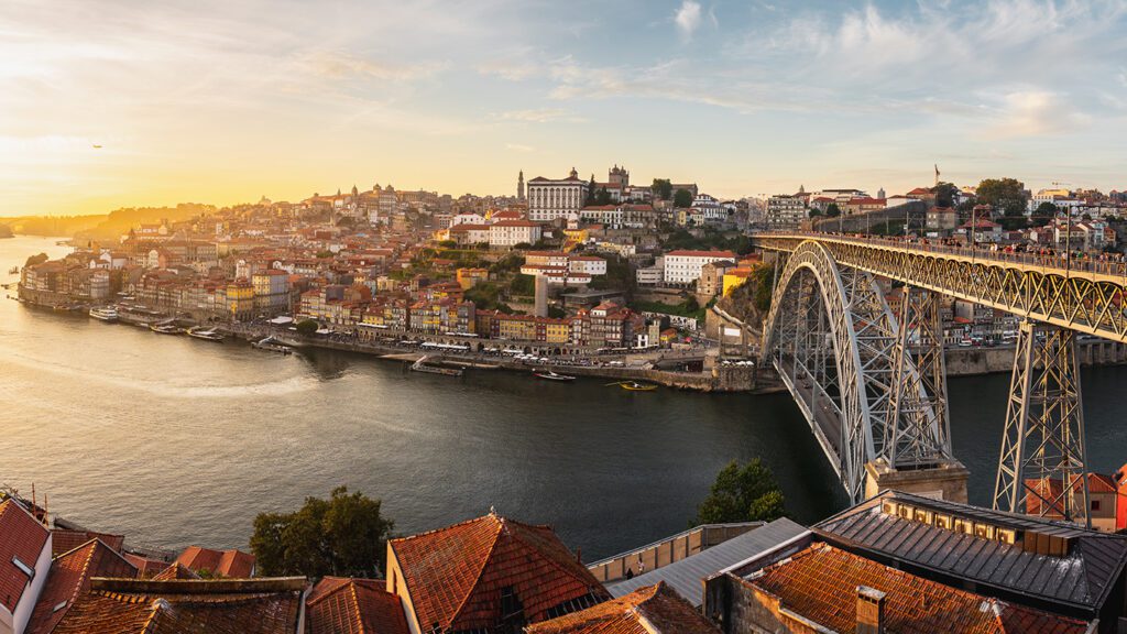 Panoramic view of local Porto, Portugal, with the Dom Luis I Bridge over the Douro River at sunset.