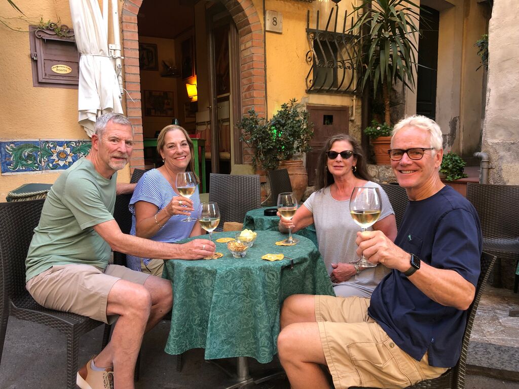 Four people toasting glasses of white wine