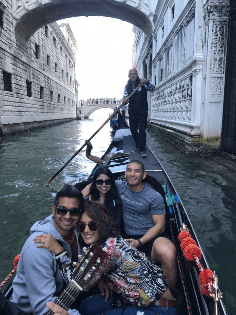 Two couples posing for a photo in a gondola in venice