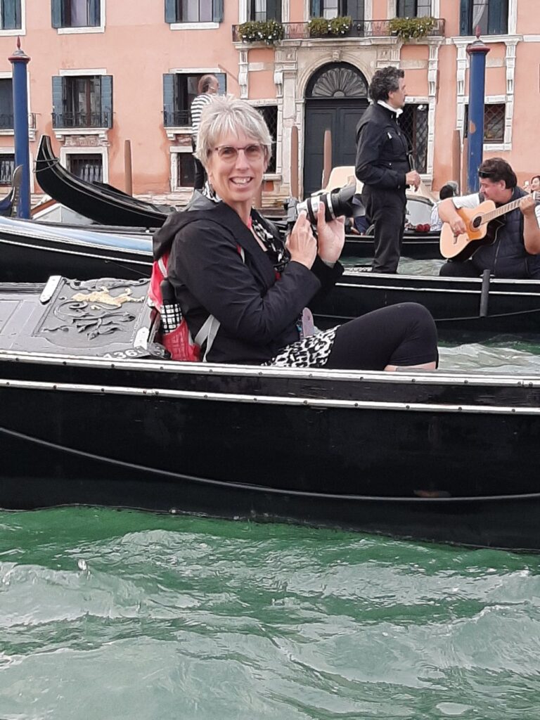 Woman sitting in gondola smiling with a camera