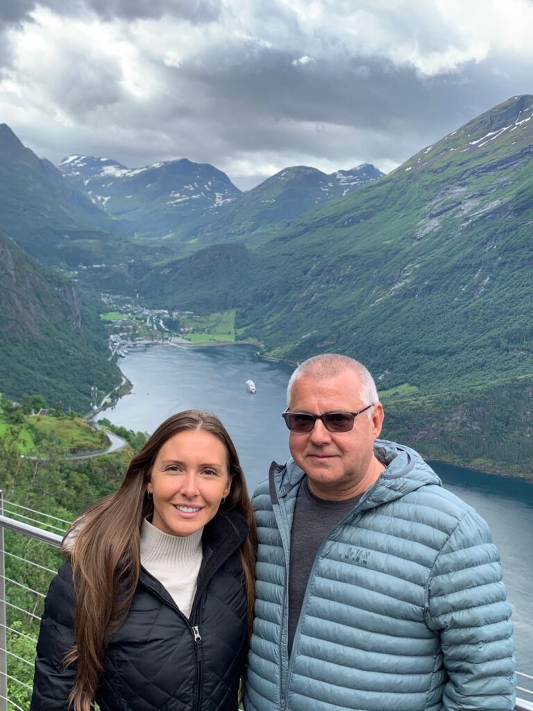 Daughter and Father posing for photo with fjord in background.