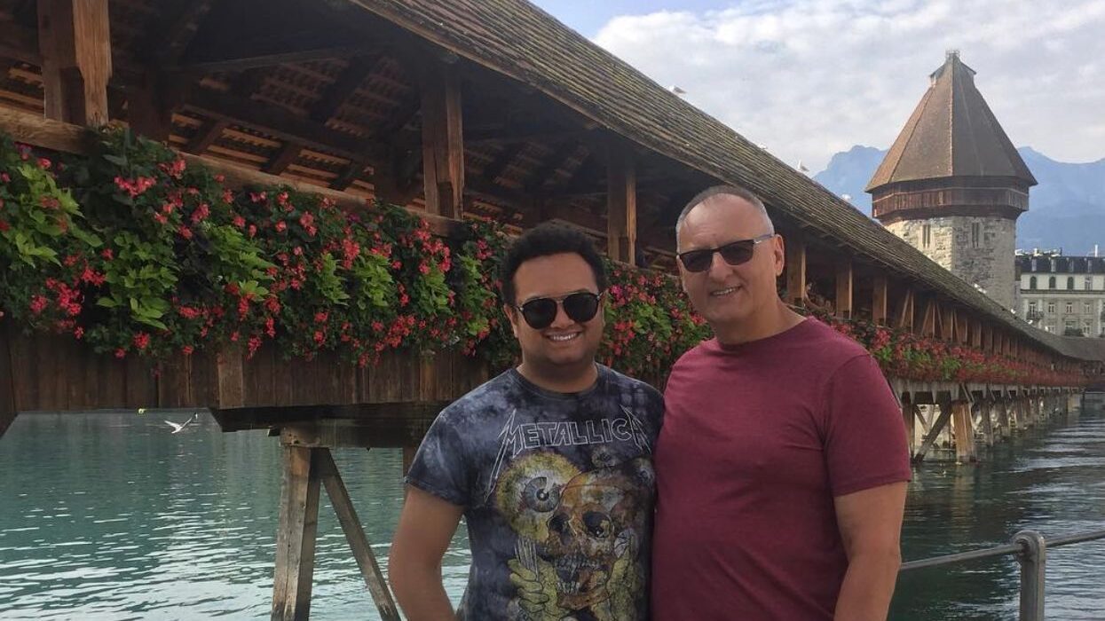 Father and Son posing for a photo in front of a bridge with flowers adorned on the side.