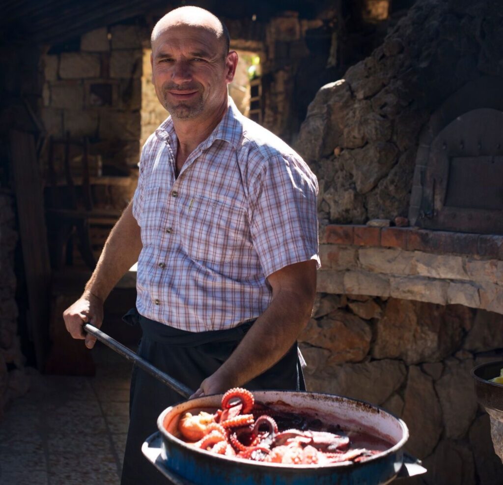 man holding pan of grilled octopus in Hvar, Croatia Trafalgar Be My Guest experiences