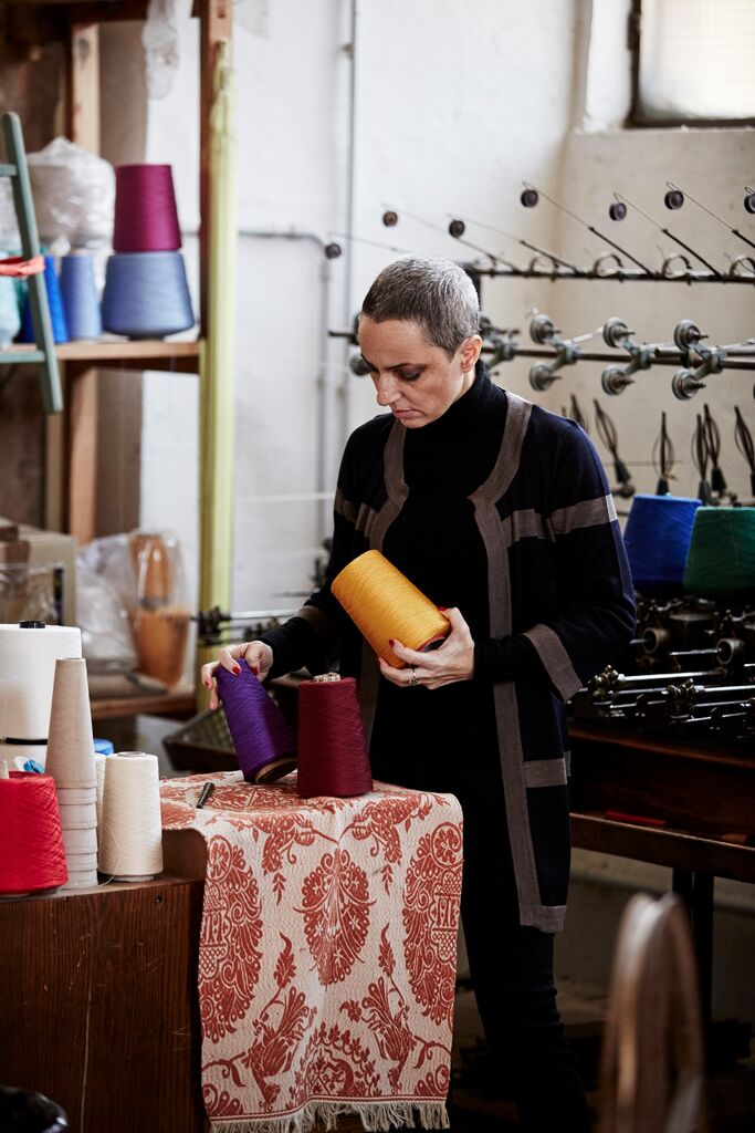 Marta Cucchia holding fabric and threads in a workshop