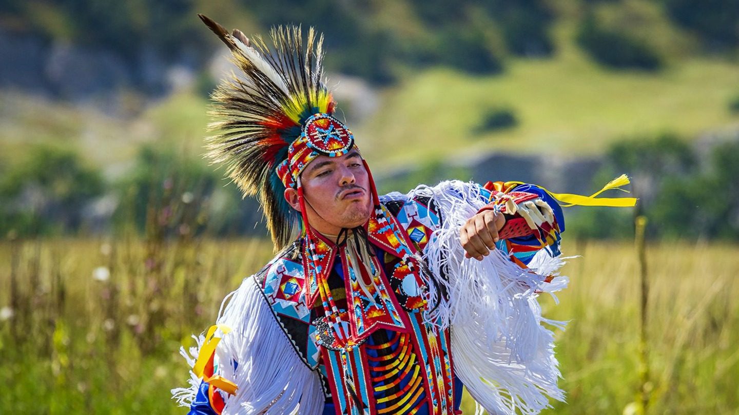 man dancing in Native American traditional regalia local communities