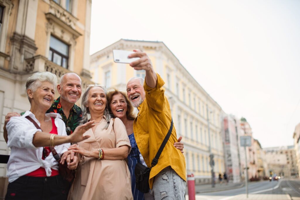 A group of mature travelers posing together or a selfie photo in front of a building