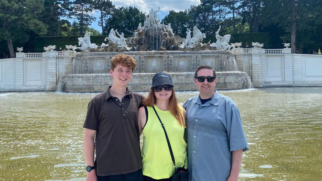 Paul with his wife and son standing in front of a large fountain