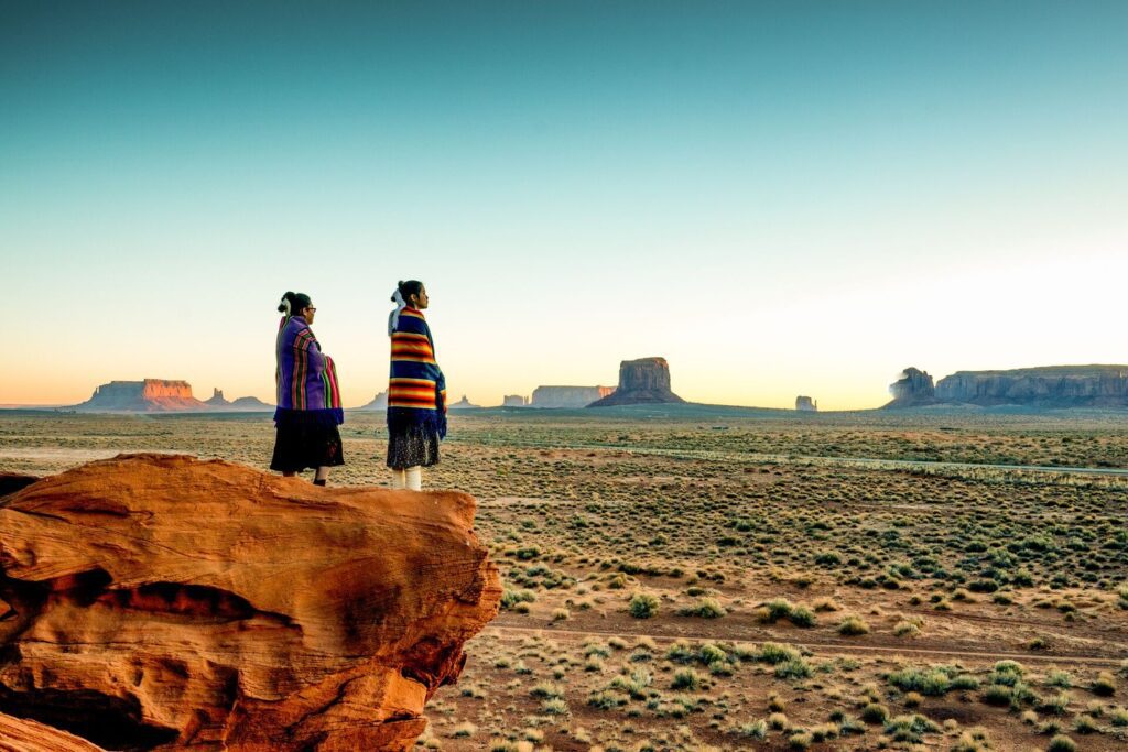 two Navajo women watching the sunrise over Monument Valley