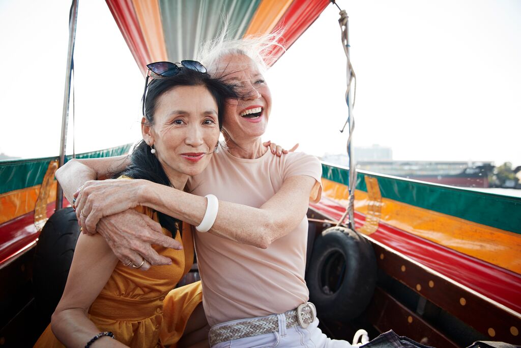 Two women in a boat are smiling and laughing, holding each other in their arms.