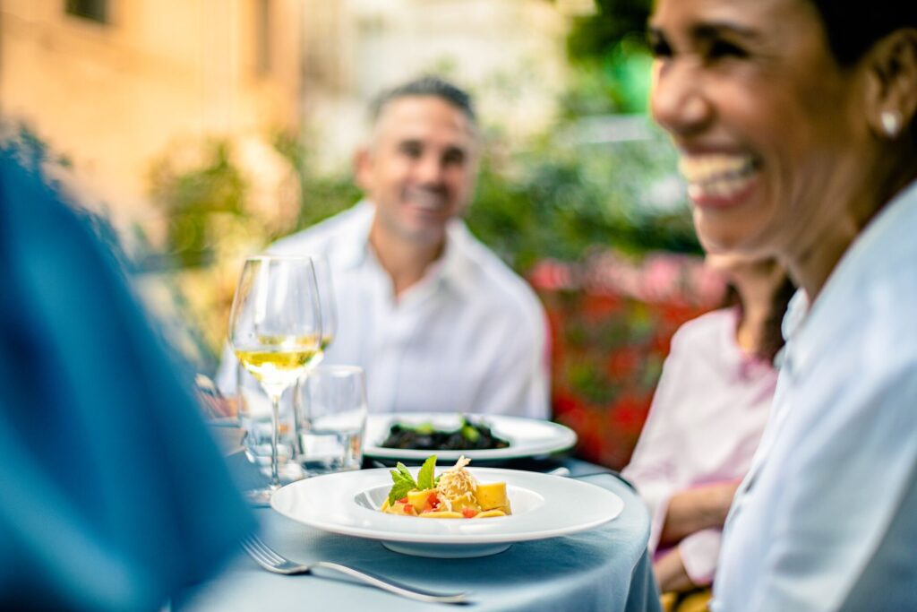 Group of travelers sit at a dining table with food in focus in front of them