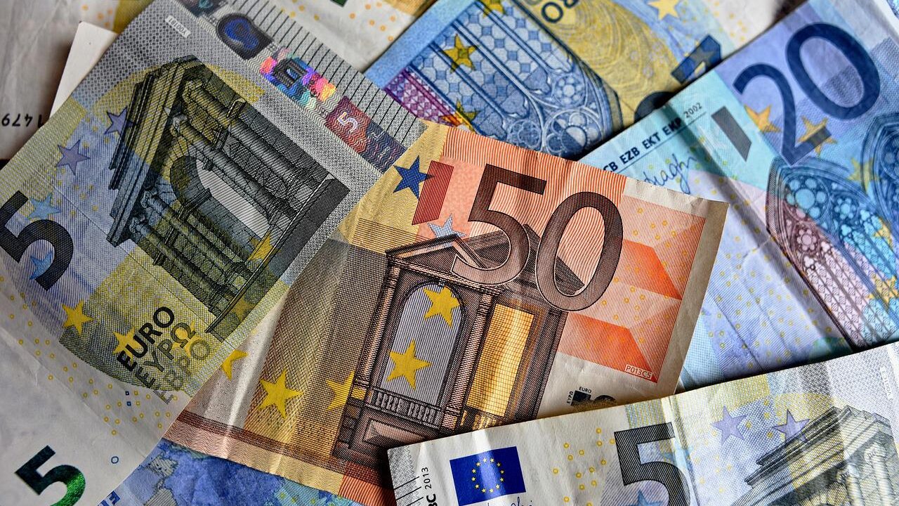 Various Euro and US dollar banknotes spread out, showing different denominations and colorful designs.